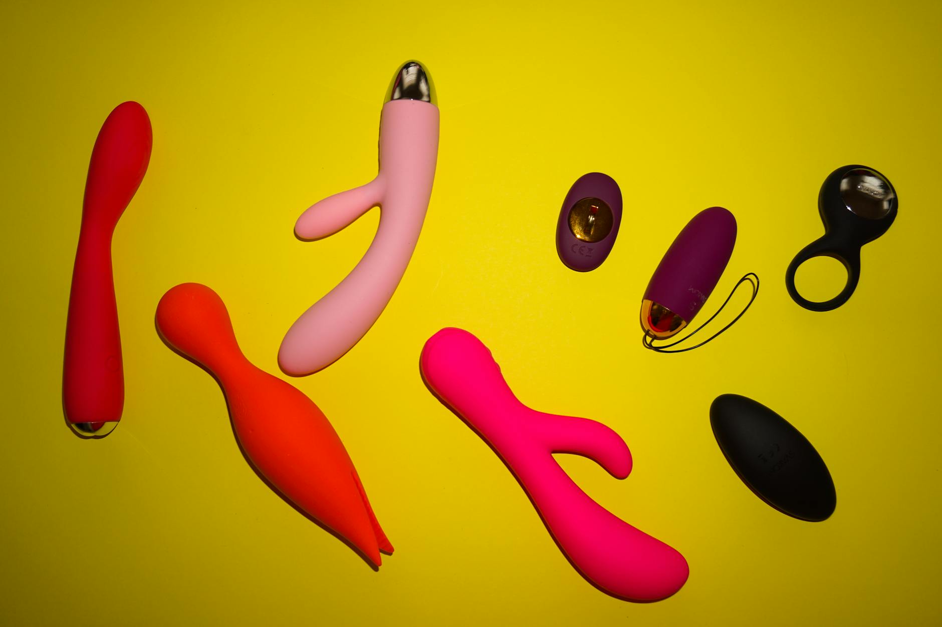 Vibrant display of various clitoral vibrators arranged on a bright yellow surface