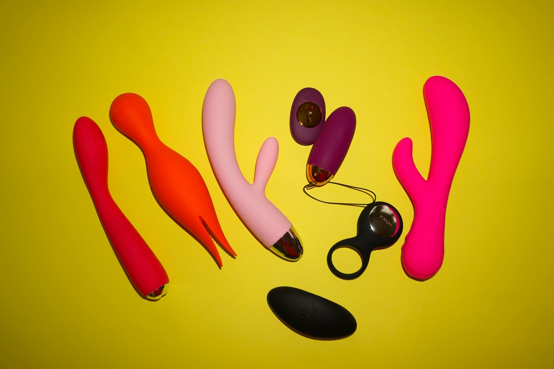A yellow silicone lemon vibrator surrounded by fresh lemons on a bright yellow background