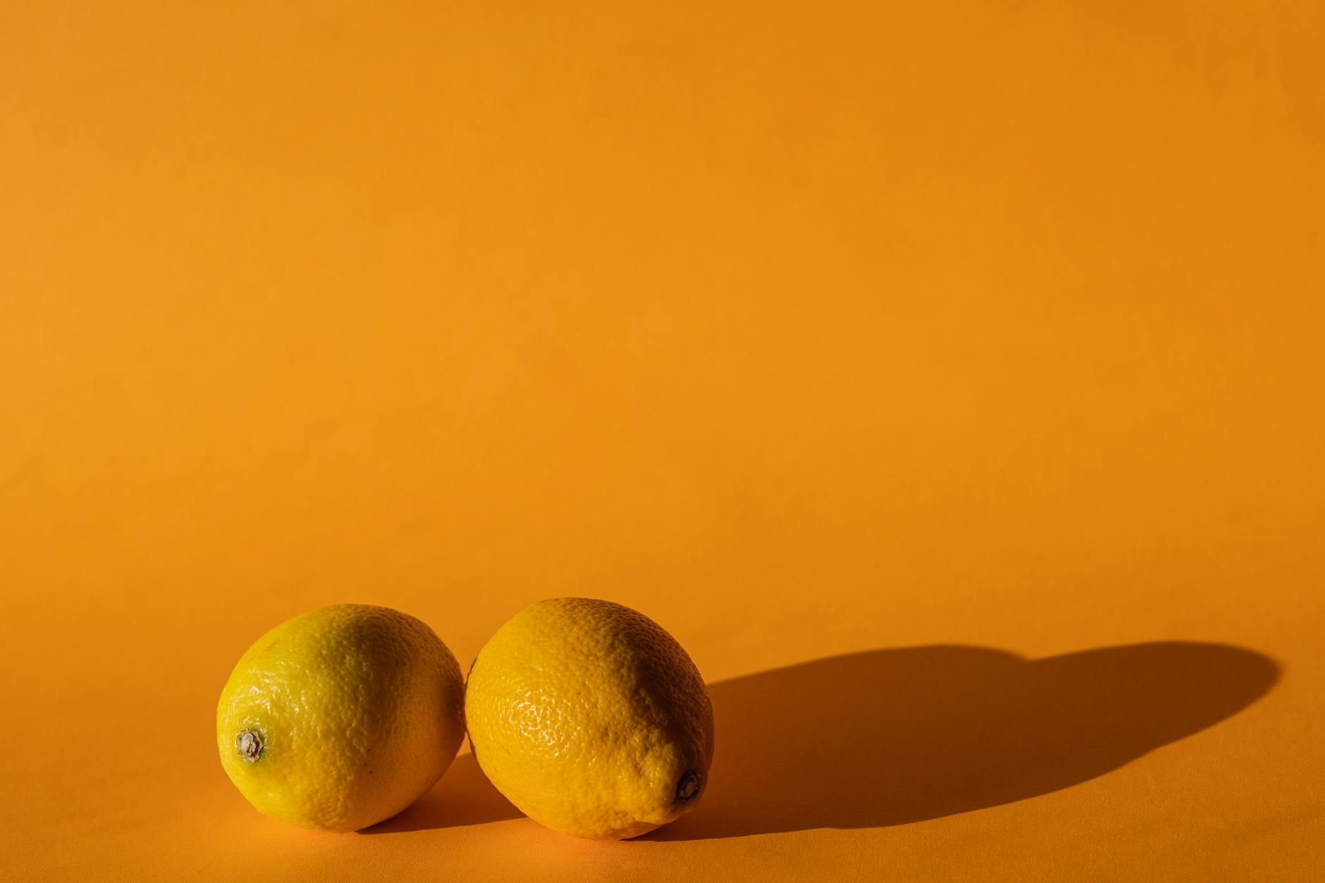 Yellow silicone vibrator surrounded by fresh fruit on bright background